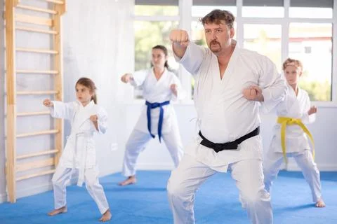 Man practicing kata routine during join family training at karate class Stock Photos