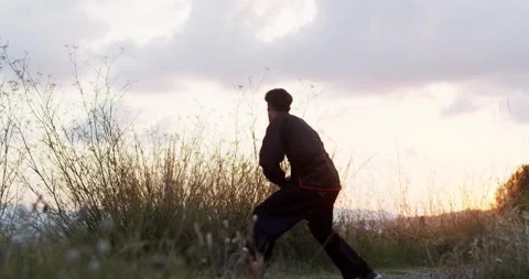 Man practicing kung fu in nature during a sunrise. Stock Footage 136026948