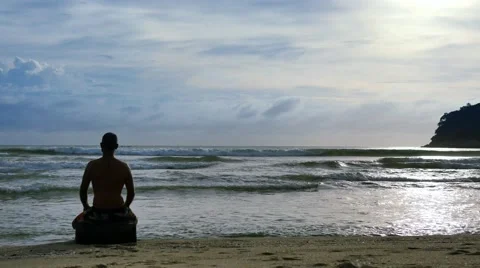 Man practicing meditation on the beach at sunset time Stock Footage 67476101
