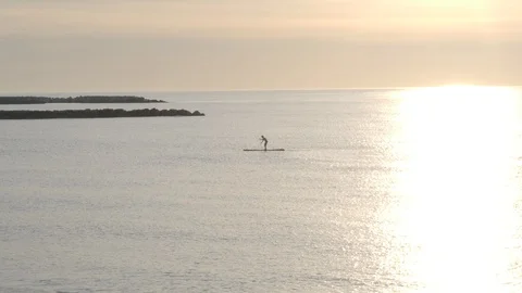 Man practicing paddle surf during sunrise at sea Stock Footage 129655515