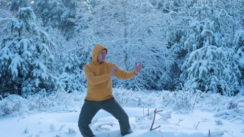Man practicing qigong breathing exercise in snowy winter forest Stock Footage 336049927