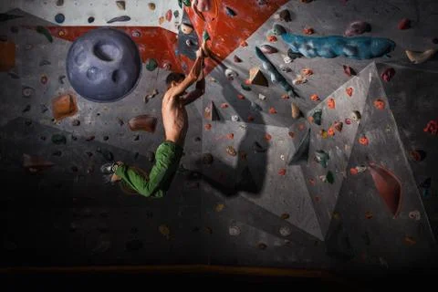 Man practicing rock-climbing on a rock wall indoors Stock Photos