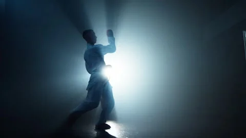 Man practicing shadow fight in smoky gym. Silhouette of professional fighter Video stock 277149648