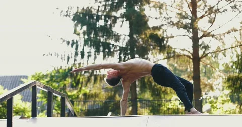 Man practicing a single hand balance pose focusing on backbend.Yogi doing Stock Footage 158508660