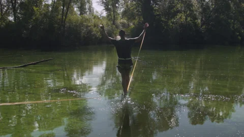 Man practicing slackline over the surface of the river 스톡 동영상 140683963