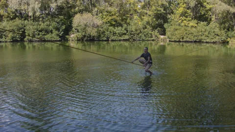 Man practicing slackline over the surface of the river 스톡 동영상 140694274