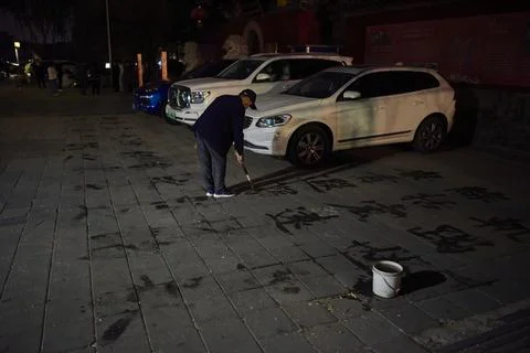 Man practicing water calligraphy (ground writing - dishu), popular pastime .. Stock Photos
