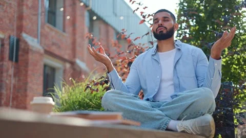 Man practicing yoga and doing ardha padmasana exercise in half lotus pose Stock Footage 250391511