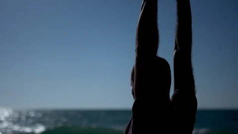 Man practicing yoga and tai chi at sunset at the beach. Slow motion Silhouette Video stock 100174376