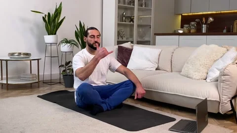 Man practicing yoga breathing exercise watching video tutorial at home Vídeos de archivo 229796445