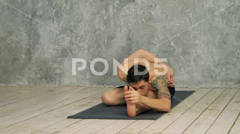 Man practicing yoga in half hero stretch pose Stock Photos