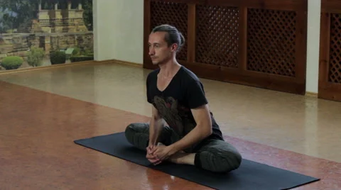 The man practicing yoga in the hall. The incline to the legs while sitting. HD Stock-Footage 65405559