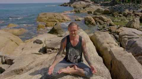 Man practicing yoga in the lotus position on seaside rock Stock-Footage 74775621