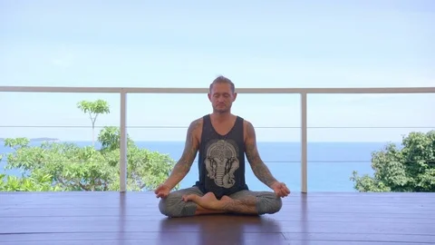 Man practicing yoga in the lotus position in gazebo Stock Footage 74779205