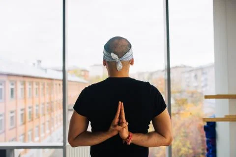 Man practicing yoga meditation pose, looking to the street through a window Stock Photos