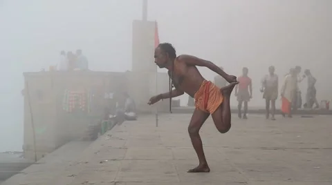 Man practicing yoga at shore of Ganges, with people passing. Stock Footage 50497734