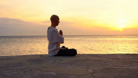 Man practicing Yoga at sunset by the sea Stock Footage 96678802
