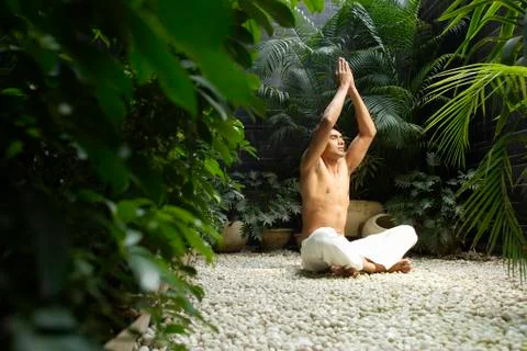 Man practicing yoga surrounded by plants Stock Photos