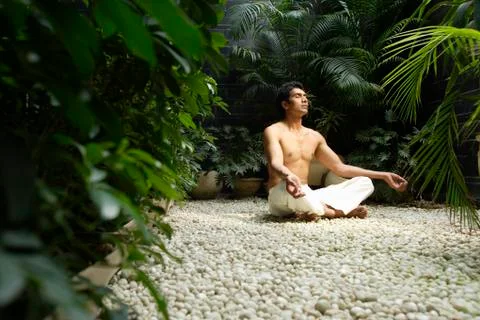 Man practicing yoga surrounded by plants Stock Photos