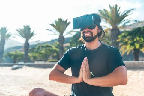 A man practicing yoga virtually while wearing a virtual reality headset and.. Foto stock