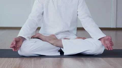 Man Practicing Yoga in a Yoga Studio. He Sits in Ardha Padmasana and meditates. Stock-Footage 59729590
