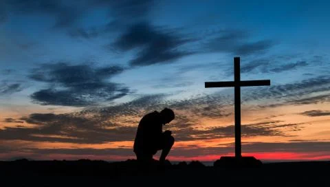 Man at prayer cross Stock Photos