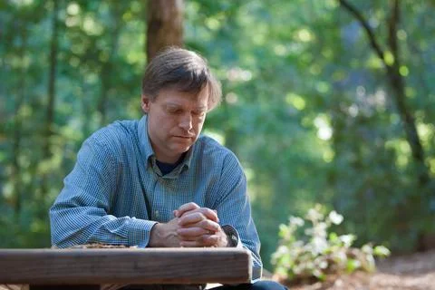 Man praying alone in middle of forest Stock Photos