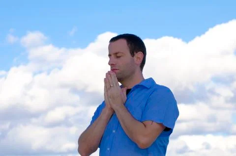 Man praying with the clouds in the background. Stock Photos