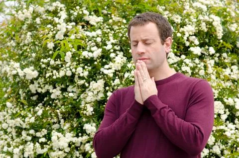 Man praying with his hands interlocked in front of white flowers. Stock Photos