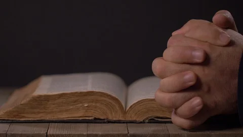 Man Praying Indoors With Hands over Old Bible. Stock-Footage 129689278