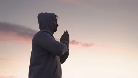 Man praying on a pink sky background, believe in good good, ask for help, dream Stock Footage 166282116