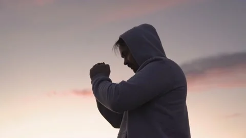 Man praying on a pink sky background, believe in good good, ask for help, dream Stock Footage 166380222