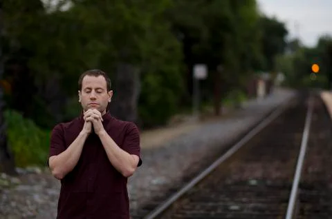 Man praying by train tracks alone. Stock Photos