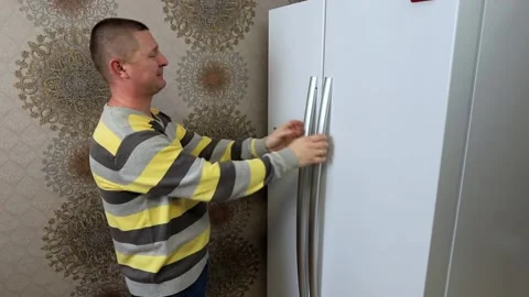 A man prays in front of the refrigerator that there would be delicious food in Stock Footage 167650524