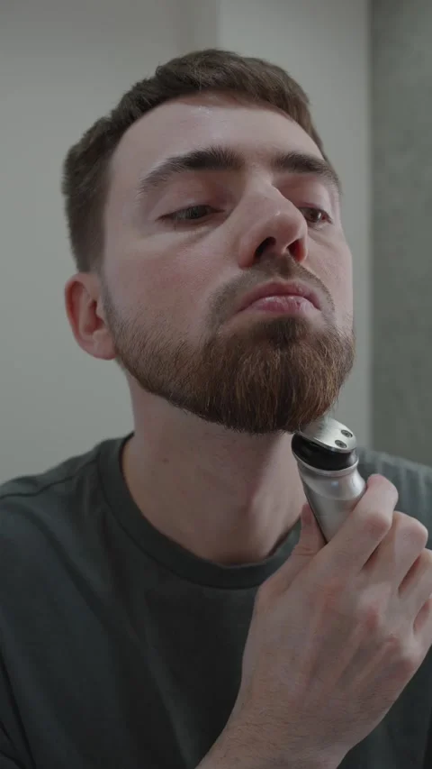 Man precisely sculpts his chin area using small trimmer 動画素材 333332158