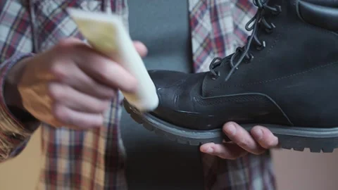 Man prepares black suede boots before fall and winter by applying a protective Stock Footage 291902132