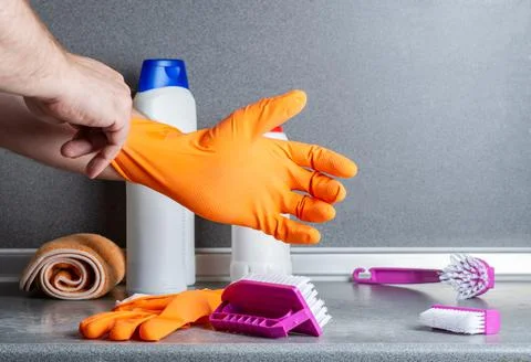 A man prepares to clean the kitchen. Puts on a rubber glove against the backg Stock Photos