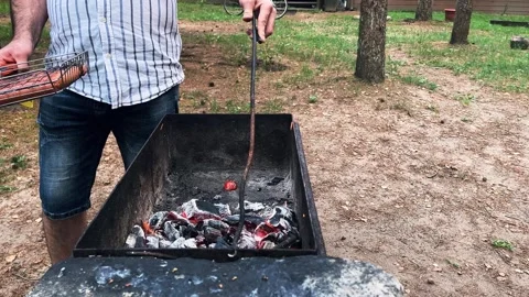 A man prepares coals for grilling Stock Footage 277458471