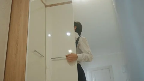 Man prepares confidently. Individual adjusts attire carefully in corridor. He Stock Footage 337231387