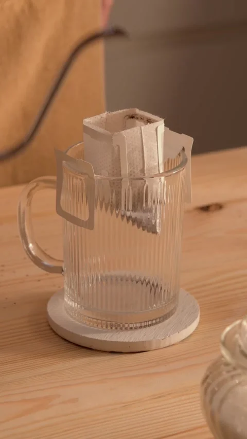 Man prepares drip coffee by placing filter into glass mug and pouring hot water Stock Footage 318005469