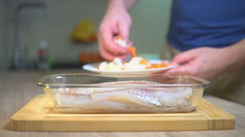 A man prepares fish with vegetables Stock Footage 101553648