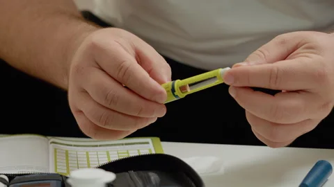 Man prepares to inject insulin using a pen for blood sugar management Video stock 302423434