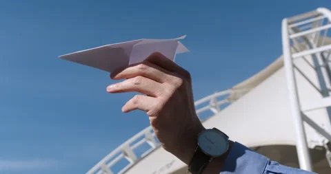 Man prepares to launch paper airplane against blue sky Vídeos de archivo 170155492