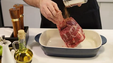 A man prepares meat for cooking generously sprinkling seasoning The seasoning Stock Footage 270363028