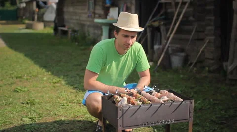 Man prepares meat on the fire. Twists meat over a fire in the garden Stock Footage 64663217