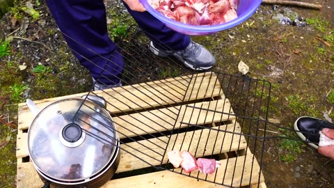 A man prepares meat, a man puts meat on a metal grid Stock Footage 151464773