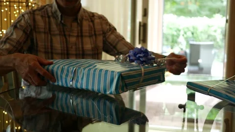 Man prepares to open birthday present at kitchen table Video stock 210873529