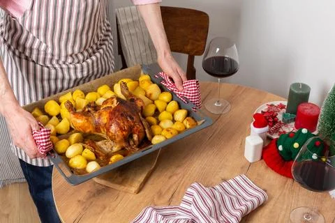 A man prepares a pre-Christmas dinner in his kitchen. He places a tray of bak Stock Photos