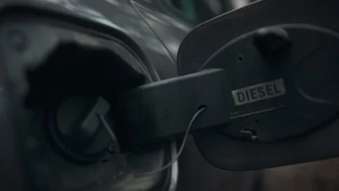 A man prepares to refuel his car by opening the gas cap on the road. The tan Stock Footage 331452460