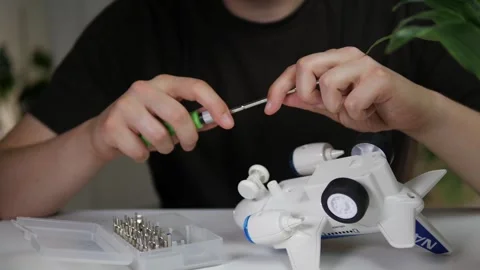 A man prepares to repair or replace batteries on a toy airplane, choosing Stock Footage 313866829